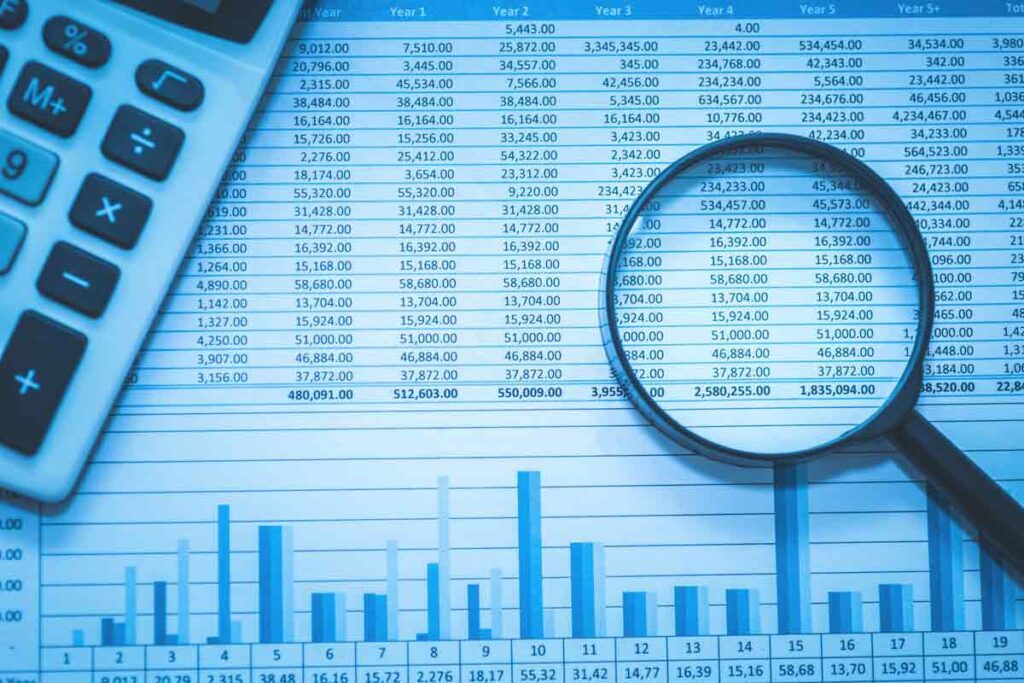 magnifying glass and calculator on top of a spreadsheet