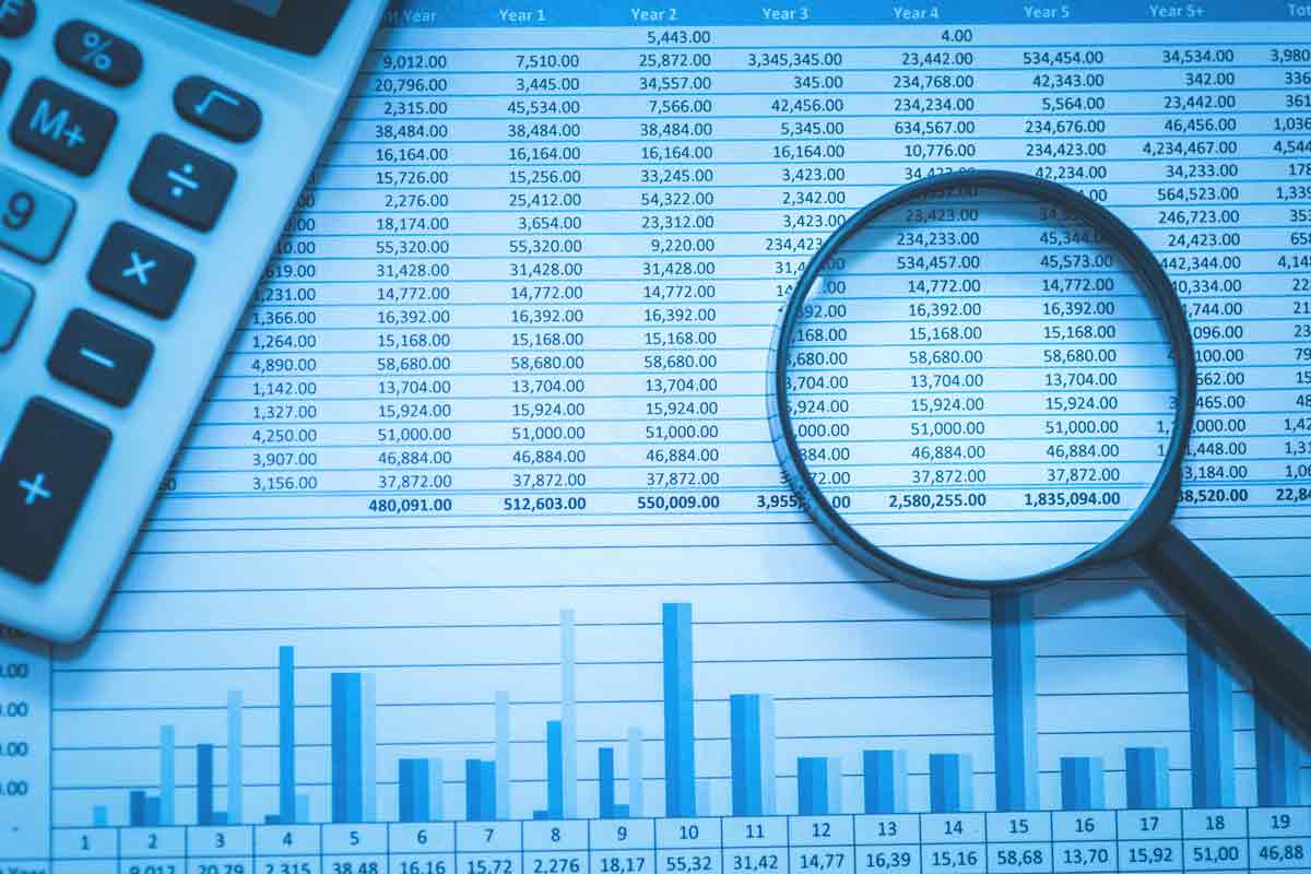 magnifying glass and calculator on top of a spreadsheet