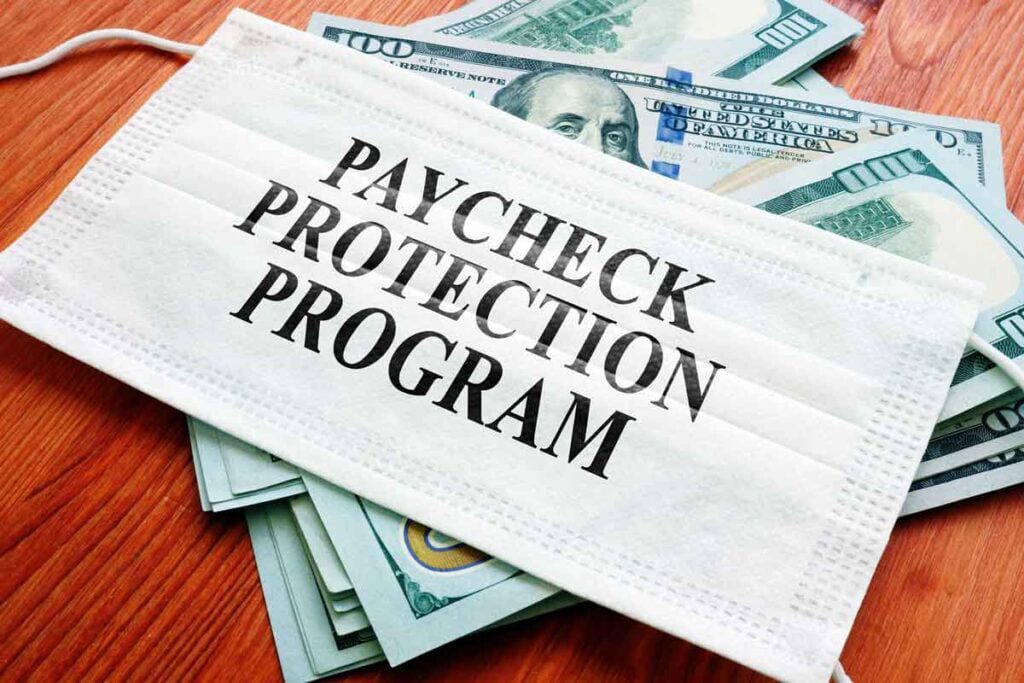 "Paycheck Protection Program" written on a mask atop money