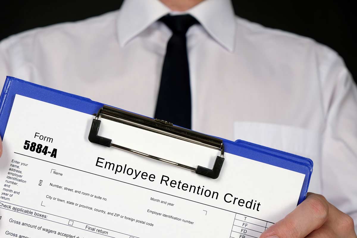 man in tie holding clipboard with paper on it saying "employee retention credit"