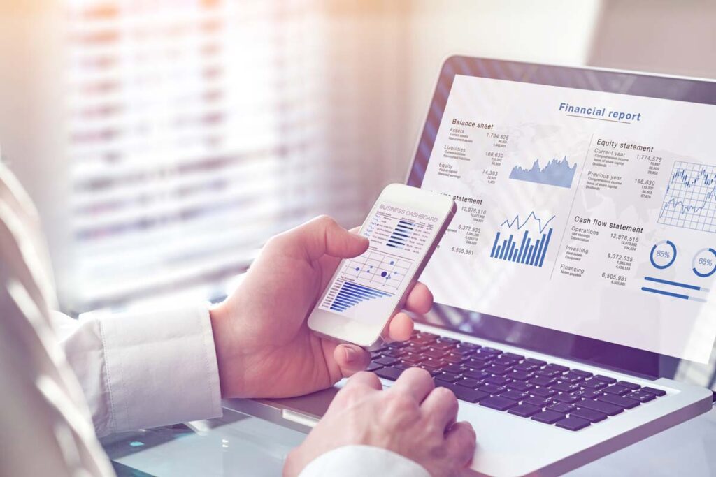 hands working on a computer and phone, computer read "financial report"