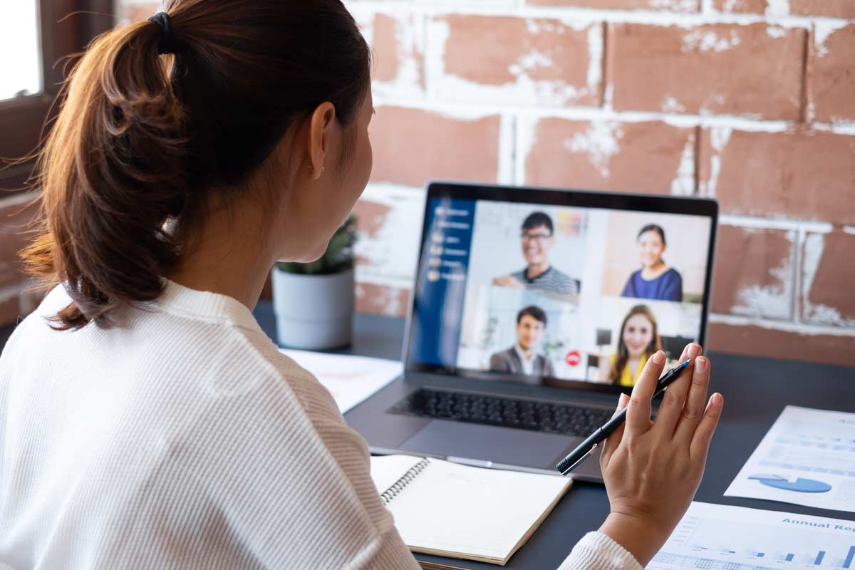 person waving a computer screen with a video call open on it