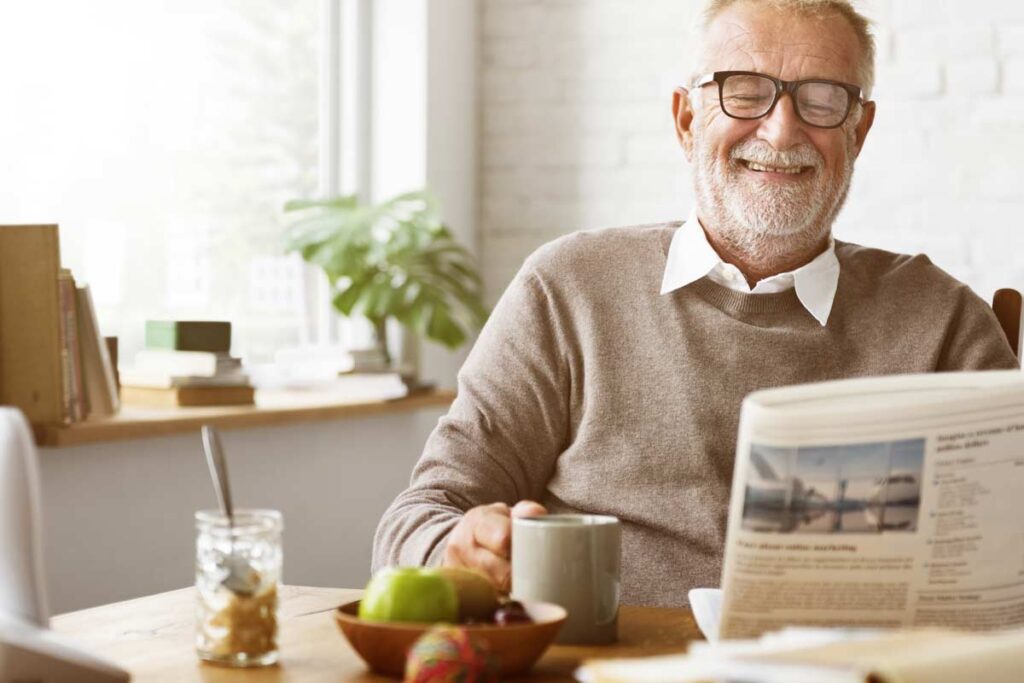 older man reading a newspaper and smiling