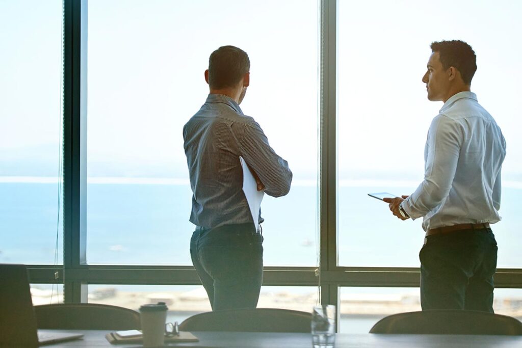 2 Businesspeople speaking while looking out the window