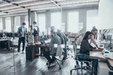 office with multiple people at desks collaborating