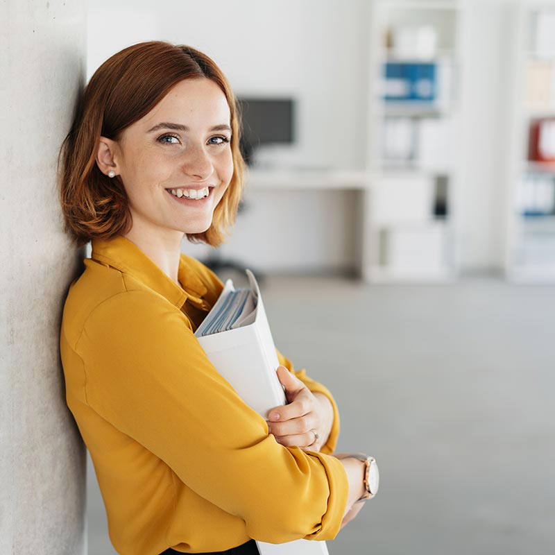 Woman smiling while holding a binder