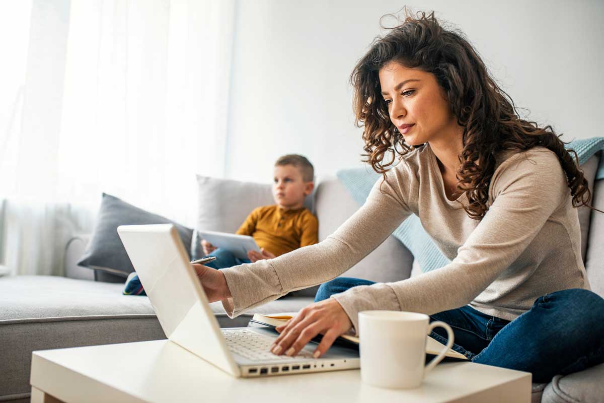 Mother sitting at computer, child in background