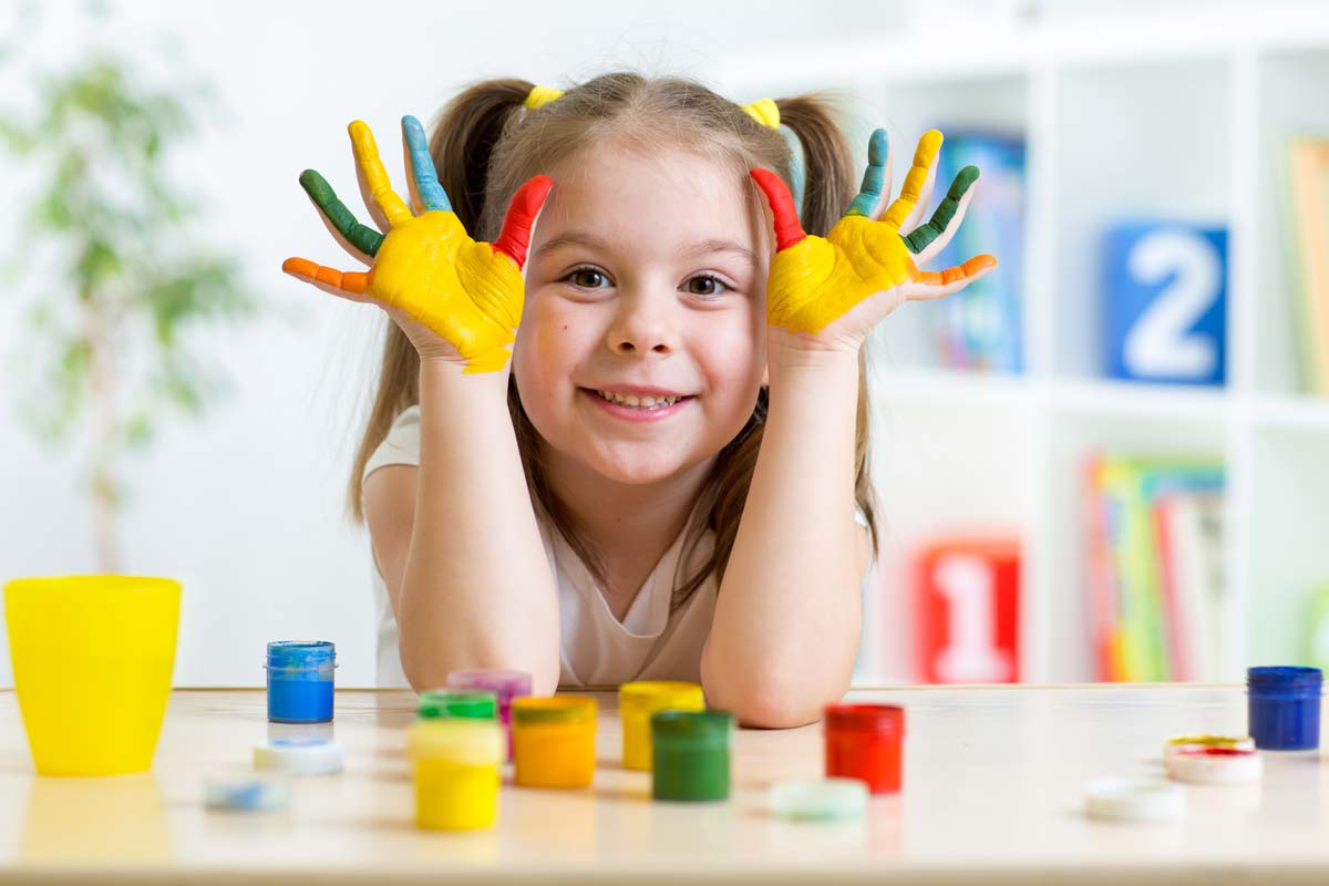 little kid smiling with paint on hands