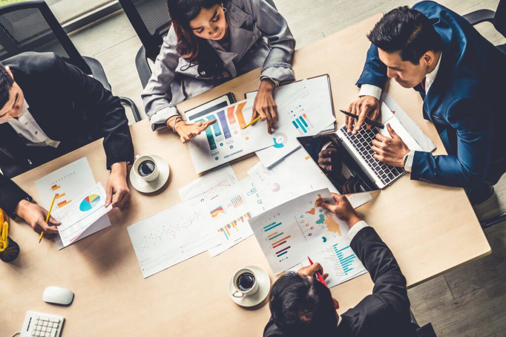 people sitting around a desk holding papers with charts