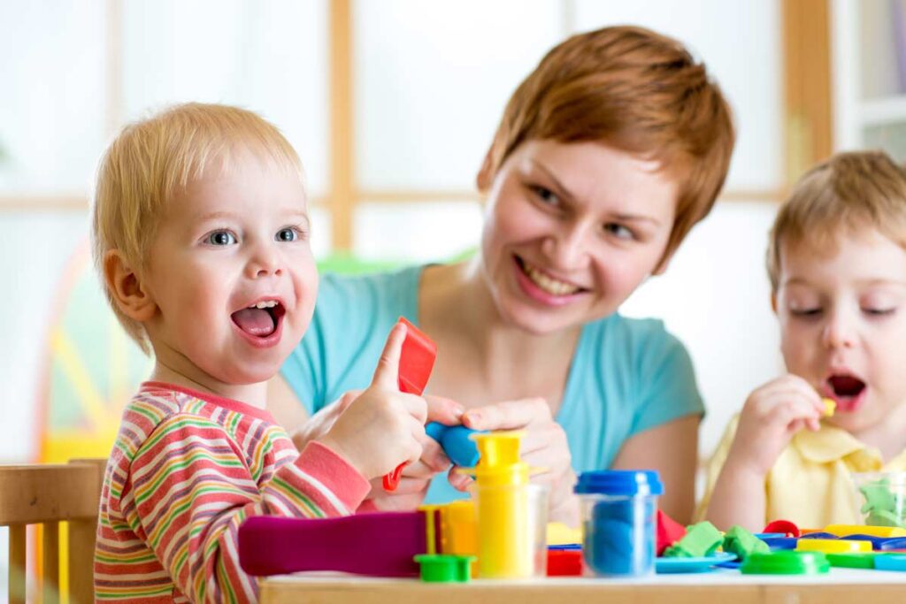 children playing with care provider at table