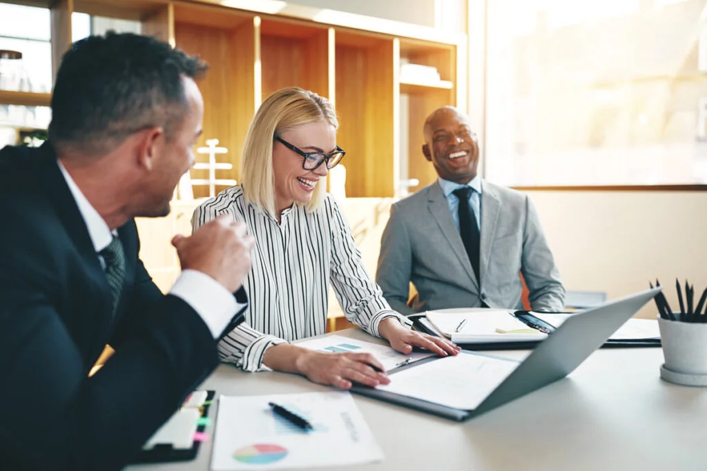 3 businesspeople laughing in a meeting room