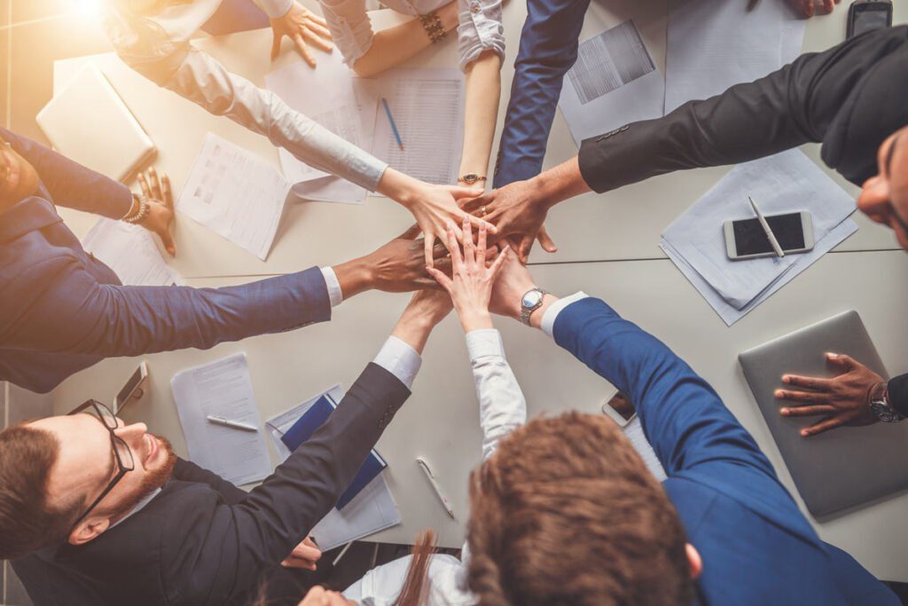 people in a meeting with their hands together