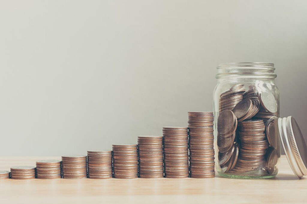 coins stacked next to a jar full of coins