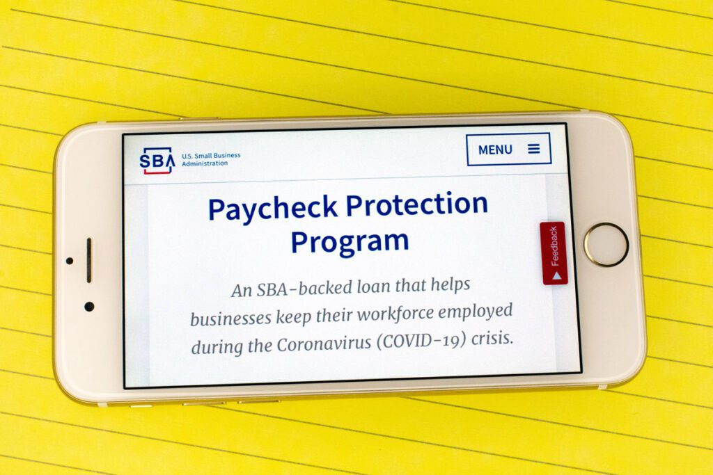 an iPhone with the words "Paycheck Protection Program - An SBA-backed loan that helps businesses keep their workforce employed during the Coronavirus(COVID-19) crisis." on it's screen