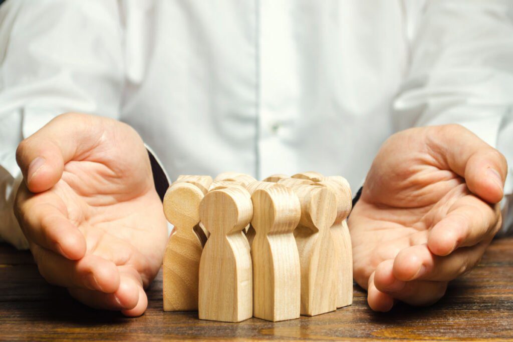 hands around wooden sculptures of people