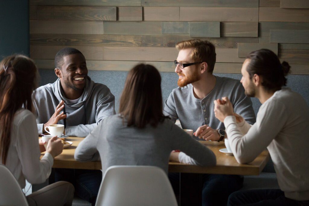 a group of friends sitting around a table smiling and talking