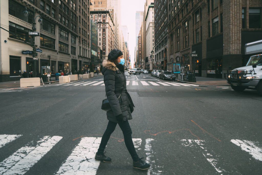 Woman crossing a city street wearing a mask