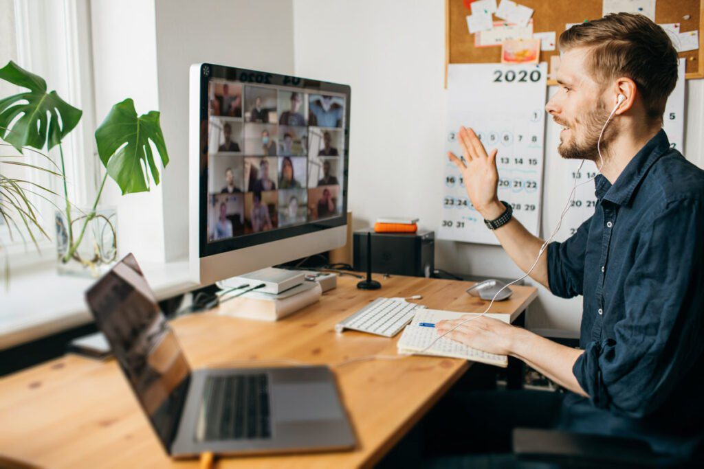 man on a video call with headphones in waving