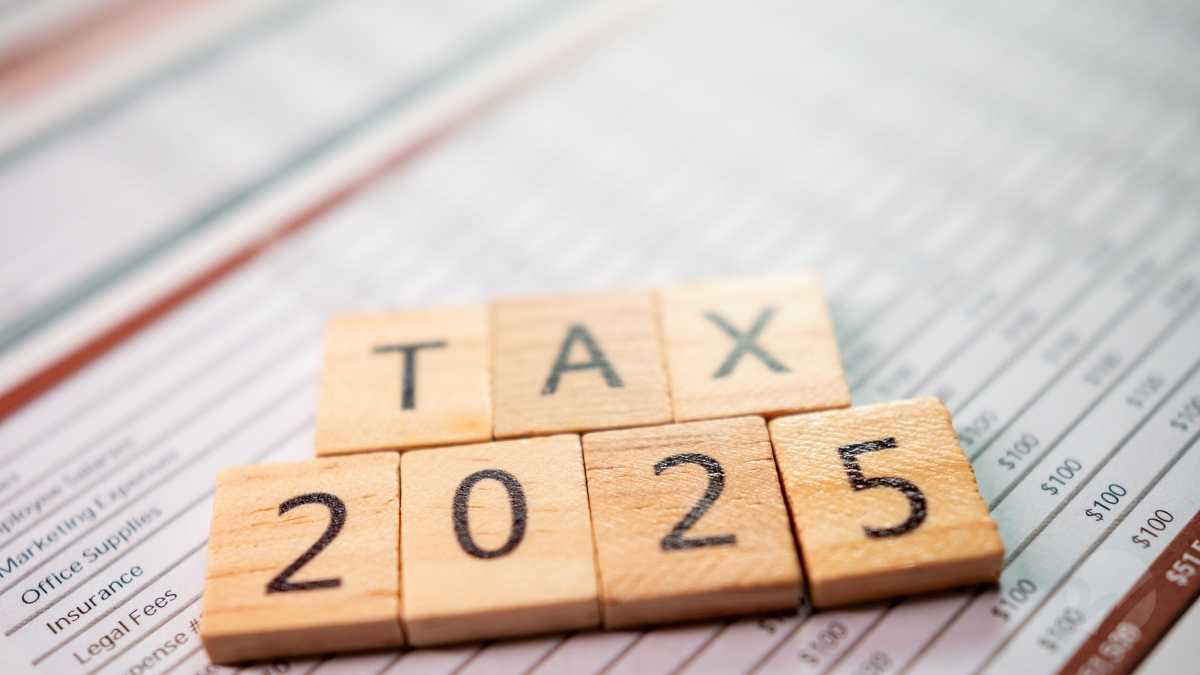 Wooden blocks spelling 'TAX 2025' placed on a financial spreadsheet, symbolizing upcoming tax law changes affecting businesses and manufacturers in 2025.