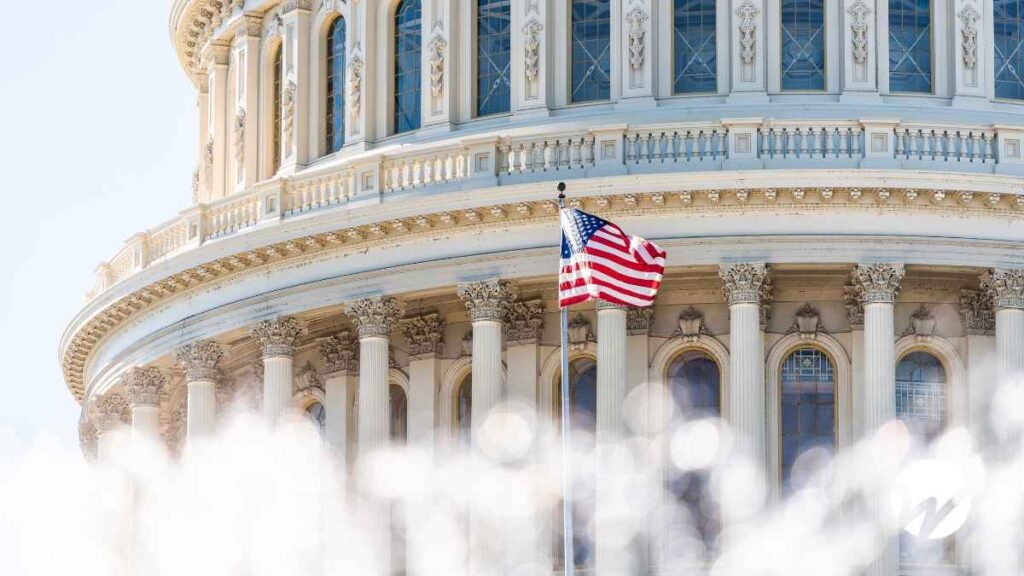 The U.S. Capitol building with an American flag waving in front, symbolizing pending federal legislation.