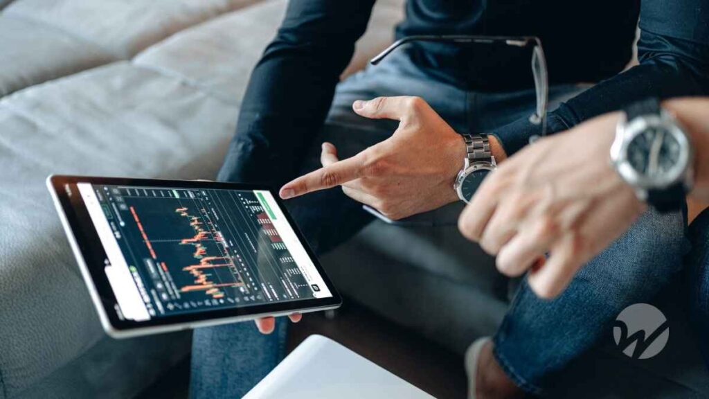 Two people reviewing cryptocurrency market data on a tablet, discussing tax implications and digital asset trends.