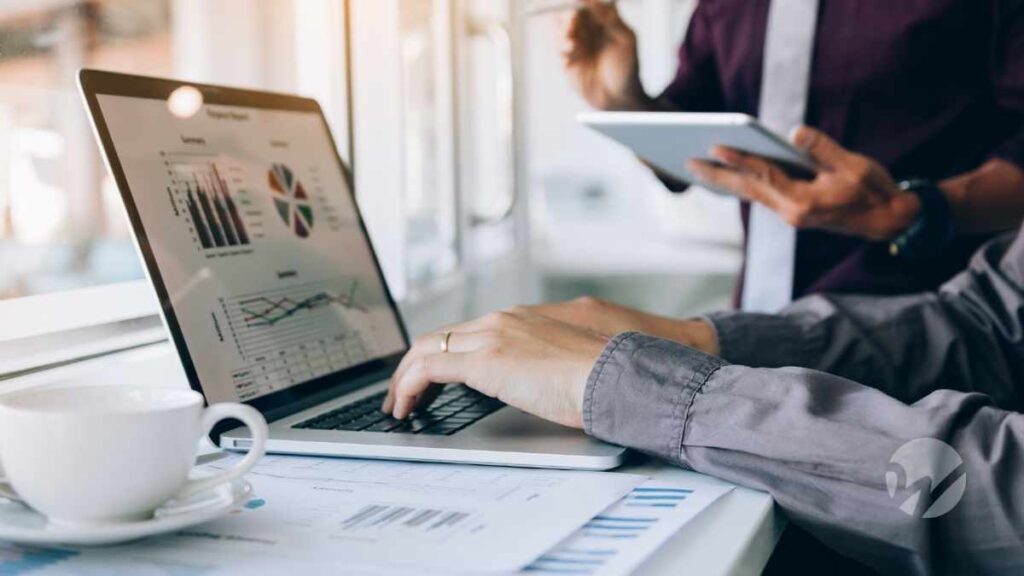 Business professionals reviewing financial charts and tax data on a laptop and tablet, representing excess business loss planning and IRS deduction rules.