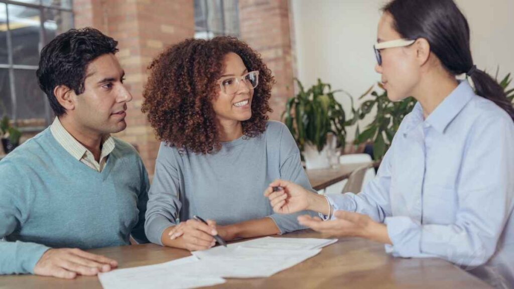 A financial advisor explaining tax changes to a smiling couple during a consultation at a modern office.
