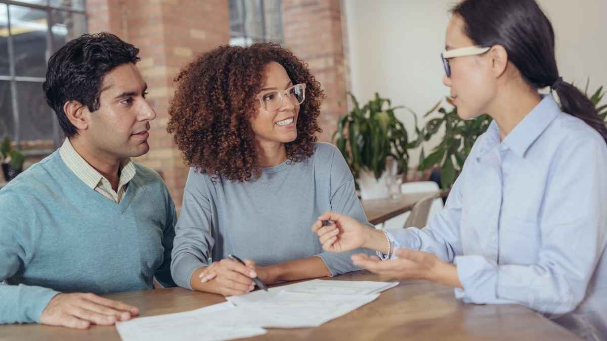 A financial advisor explaining tax changes to a smiling couple during a consultation at a modern office.
