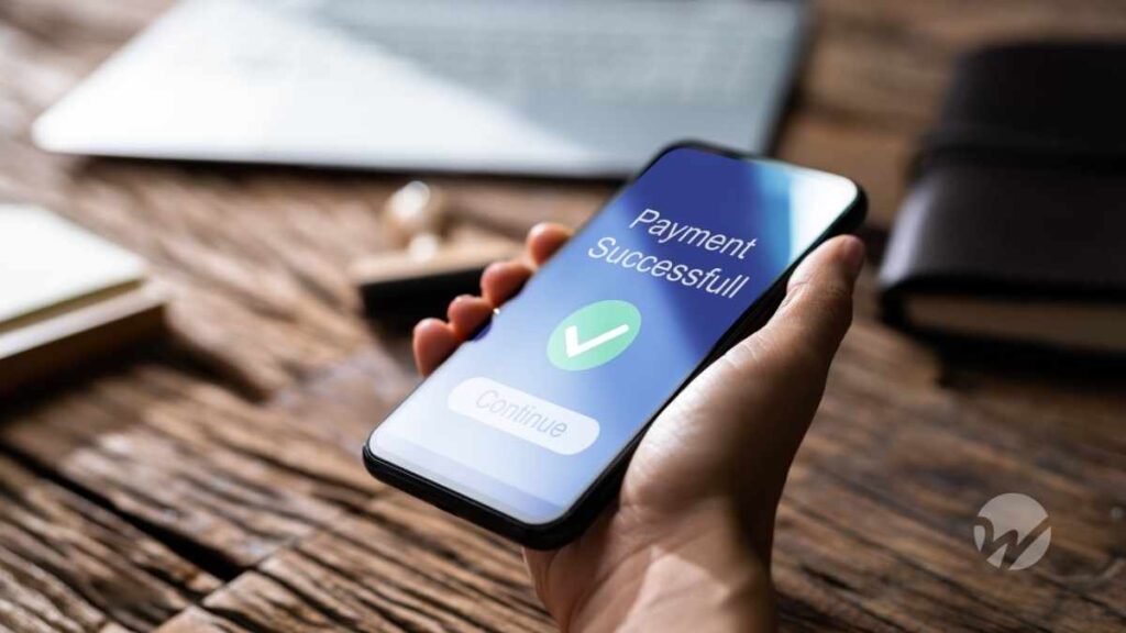 Image of hand holding cellphone displaying "payment complete" graphic