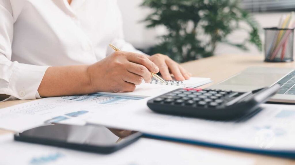 picture of hands filling out form with calculator and various documents on the desktop