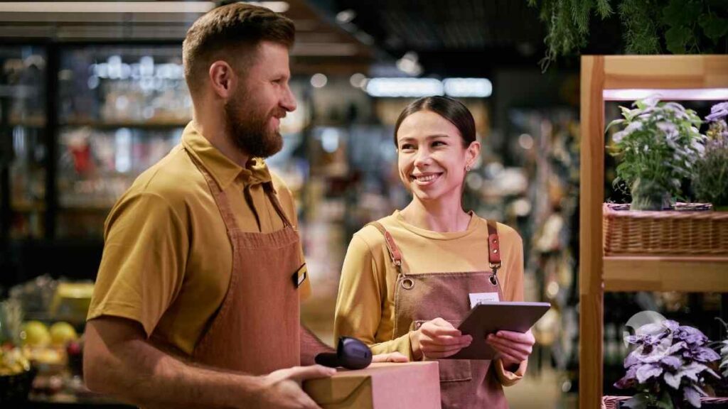 two retail employees chatting in front of rack of plants