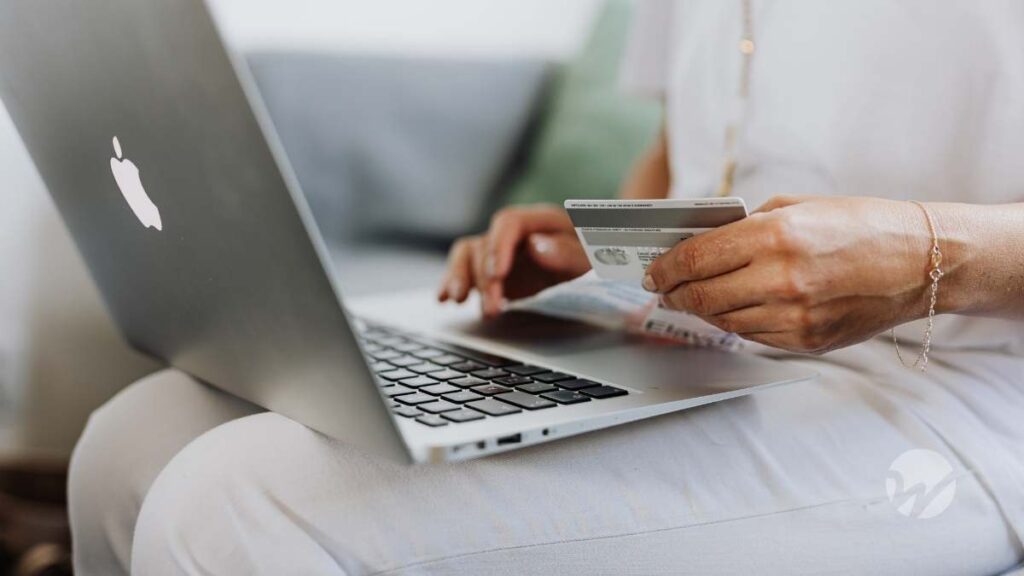 Photo of person with laptop on lap holding credit card as if about to make a payment