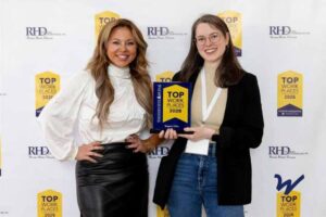 Photo of two women in front of step and repeat backdrop holding Top Workplaces 2026 Award