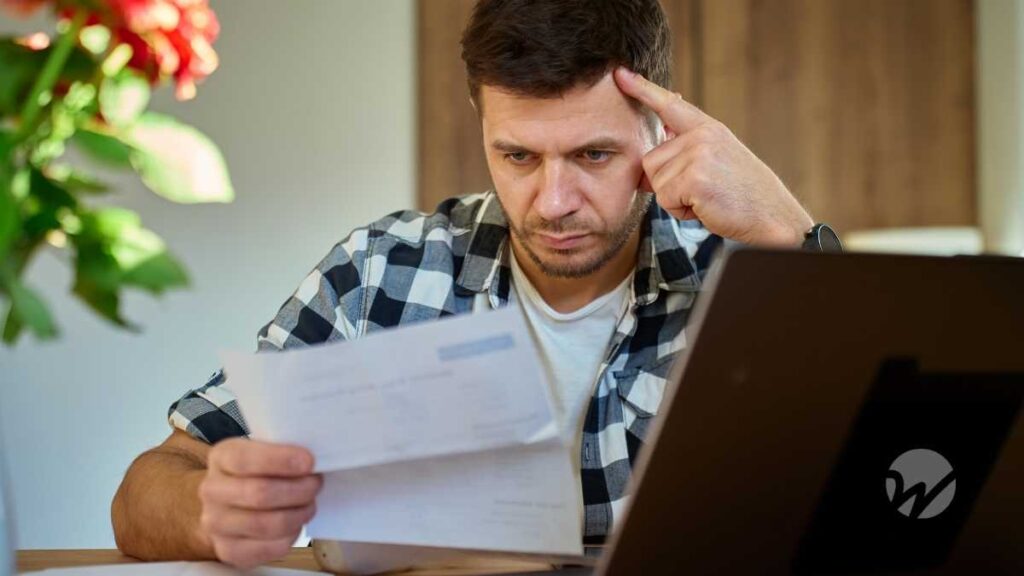 Frustrated man reading notice in front of laptop computer