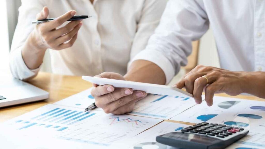 Photo of two individuals at a desk reviewing financial documents to convey “when to get a business valuation before selling”
