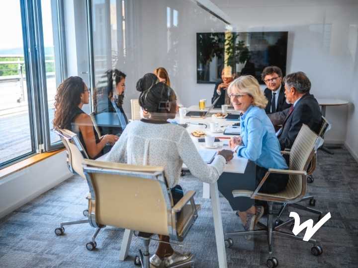 A diverse group of professionals meeting around a conference table in a modern office, representing board collaboration and audit preparation.