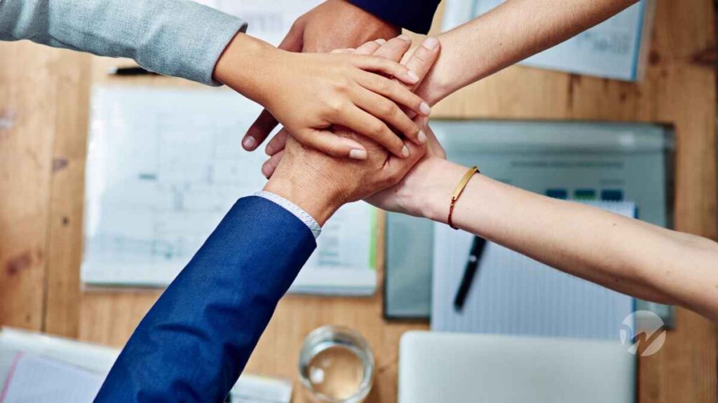Nonprofit team members stacking their hands together during a meeting.