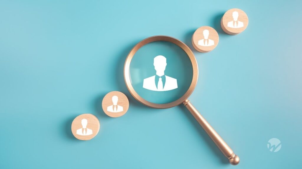 magnifying glass over icons of male figure in suit representing recruiting