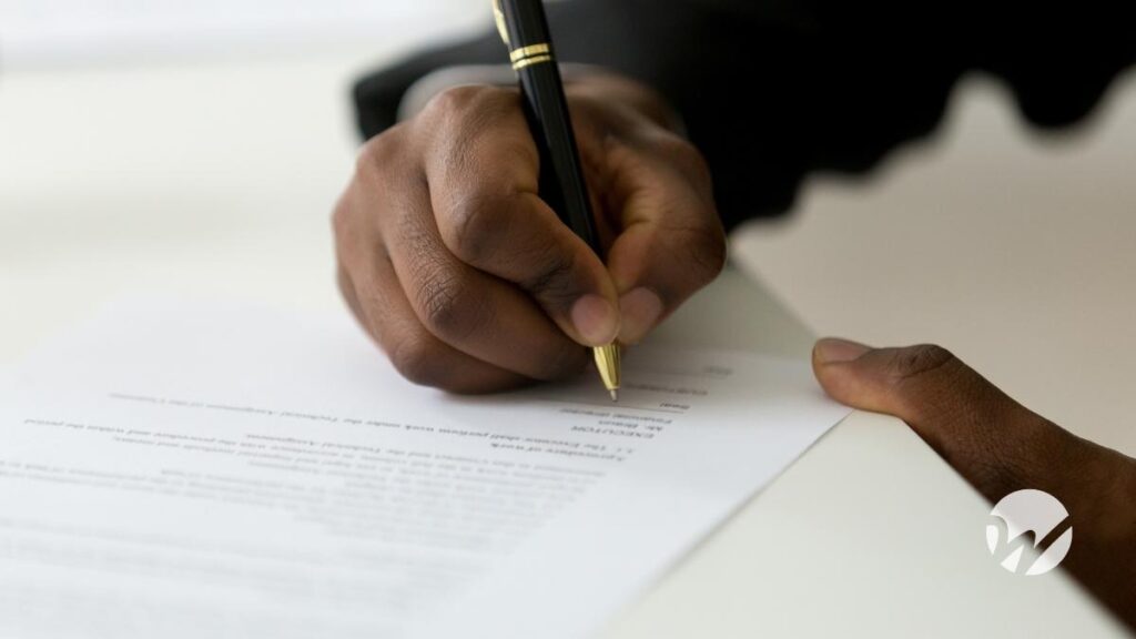 Photo of masculine hands signing a document