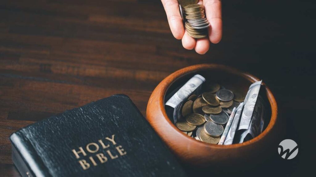 Picture of Bible next to wooden bowl full of cash donations